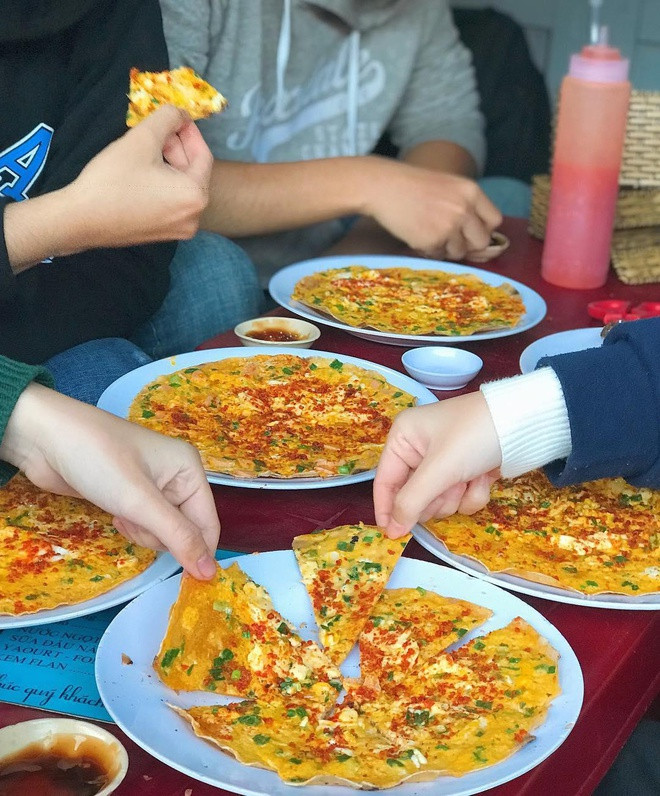 br/> Ở Ninh Thuận, Bình Thuận, món bánh tráng mắm ruốc nướng khá phổ biến. Bánh tráng được quét (phết) đều mắm ruốc, thêm trứng (sống hoặc chín), hành lá, nem, chả... nướng lên, gập thành hình tam giác hoặc cuốn tròn. Còn ở Đà Lạt, bánh tráng nướng được du khách ví như "pizza", có thành phần topping đa dạng như trứng, phô mai, xúc xích, chà bông, pa tê, tôm khô, khô bò, mỡ hành... nhưng không có mắm ruốc. Bánh tráng thường được giữ nguyên hình tròn, khi ăn thực khách tự cắt thành miếng nhỏ. Ảnh: Munchinmelon.
