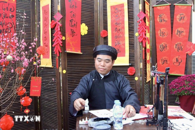 Góc Tết Việt với hình ảnh ông đồ viết thư pháp, tặng chữ bên cành đào được tái hiện. (Ảnh: Quang Anh/TTXVN)