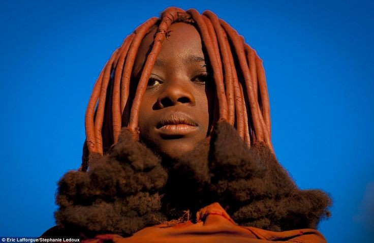  Nổi tiếng với lớp bôi da màu đỏ. Cư dân Himba thường trộn mỡ bò với bột đá ochre đỏ để bôi lên da và tóc. Hỗn hợp này giúp bảo vệ da khỏi nắng gắt, côn trùng và đồng thời mang ý nghĩa thẩm mỹ, tâm linh sâu sắc. Ảnh: Pinterest.