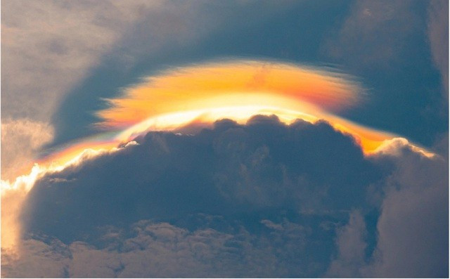 Chiều 6/6/2025, cư dân Long Biên chứng kiến một đám mây lớn kèm theo quầng ánh sáng bao quanh, tồn tại trong khoảng gần một giờ. Hiện tượng này liên quan tới tán xạ và khúc xạ ánh sáng trên các hạt mây, còn được gọi là hiện tượng quầng mây/mây ngũ sắc dạng rộng. Ảnh: Tiền Phong.