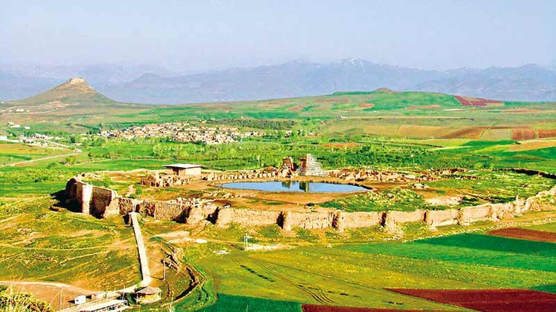  Hệ thống tường thành kiên cố bao quanh. Takht-e Soleymān được bảo vệ bởi tường đá lớn hình bầu dục, với tháp canh và cổng vào rõ ràng. Điều này cho thấy nơi đây không chỉ là trung tâm tôn giáo mà còn có giá trị chiến lược và chính trị. Ảnh: parsi-tours.com.