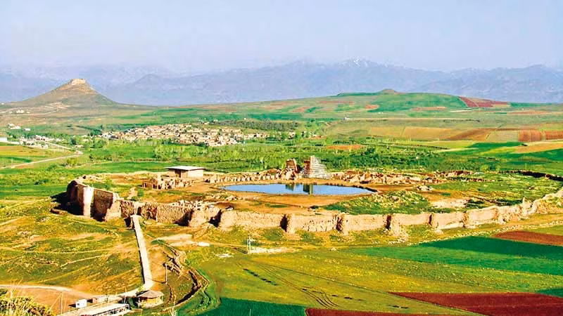  Hệ thống tường thành kiên cố bao quanh. Takht-e Soleymān được bảo vệ bởi tường đá lớn hình bầu dục, với tháp canh và cổng vào rõ ràng. Điều này cho thấy nơi đây không chỉ là trung tâm tôn giáo mà còn có giá trị chiến lược và chính trị. Ảnh: parsi-tours.com.