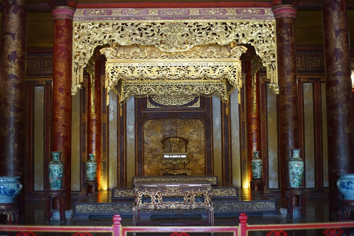 Nằm dưới chiếc bửu tán lộng lẫy. Trên ngai vàng có một chiếc bửu tán lớn treo phía trên, cũng được trang trí cầu kỳ với màu vàng và các họa tiết rồng mây. Bửu tán giúp tôn vị trí trung tâm của hoàng đế và tạo nên không gian nghi lễ trang nghiêm.