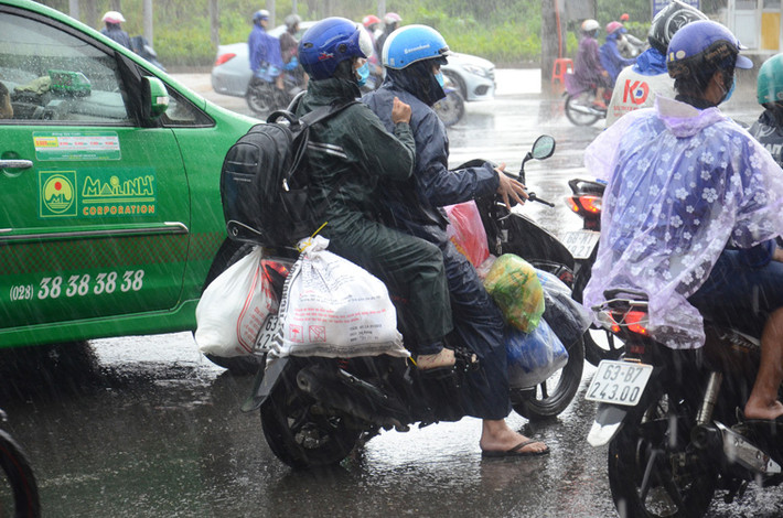 Gia đình này chở theo đồ đạc lỉnh kỉnh trở lại thành phố trong cơn mưa tầm tã.