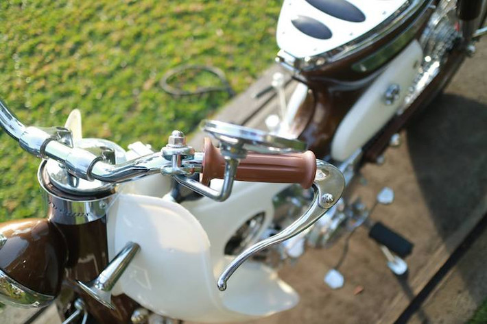 Theo đúng phong cách Street Cub, phần đầu nguyên bản của Super Cub đã được loại bỏ và thay bằng ghi-đông trần. Toàn bộ cụm "sọ khỉ" cùng tay lái và gù ghi-đông cũng được mạ chrome bóng bẩy, trong khi hai bên là cặp bao tay vỏ dưa cùng tay phanh gắn gù đậm chất cổ điển.