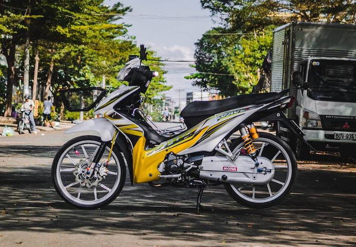 Để mừng xuân Đinh Dậu, một biker tại miền Nam đã "dọn" lại chiếc Wave S 110 của mình đầy bắt mắt theo phong cách kiểng Thái Lan với hàng loạt phụ tùng có giá trị cao. Điểm nhấn đầu tiên của chiếc xe là dàn áo màu trắng tinh khiết với điểm nhấn là bộ tem vàng tươi bắt mắt như sắc hoa mai mùa Tết.