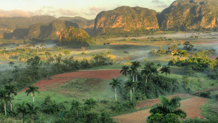 3. Thung lũng Vinales ở Cuba. Thung lũng Vinales có diện tích 132km2 nằm cách Thủ đô Havana khoảng 160km. Được bao quanh bởi các dãy núi đá vôi và những kỳ quan huyền bí như các vết nứt, các hố đào và hang động ngầm tự nhiên. Cả một vùng thung lũng ngập trong màu xanh của rừng cọ, của những ruộng thuốc lá xanh biếc, phía xa là dãy núi Sierra de Vinales dựng đứng như bức tường cũng phủ màu xanh cây lá. Bên cạnh đó thung lũng còn mang vẻ đẹp như một vùng đất cổ tích nhờ vẻ đẹp của các trang trại, làng mạc được xây dựng theo kiến trúc vernacular.
