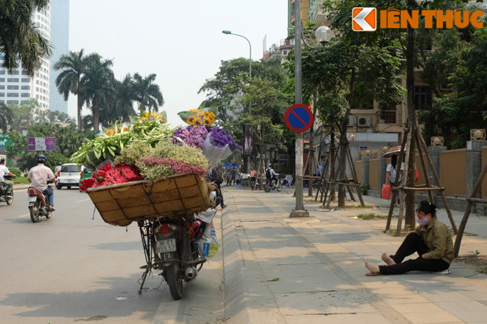 Người phụ nữ bán hoa dạo ngồi nghỉ chân dưới một tán cây xanh để tránh nắng.