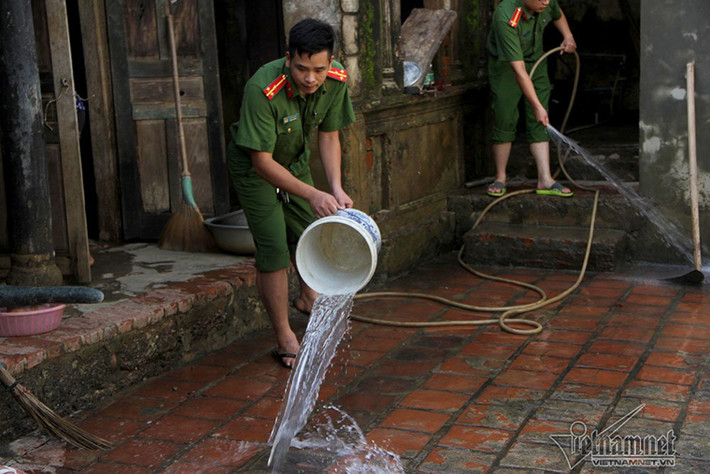 Chiến sĩ công an xắn quần dọn dẹp giúp dân sau lũ.