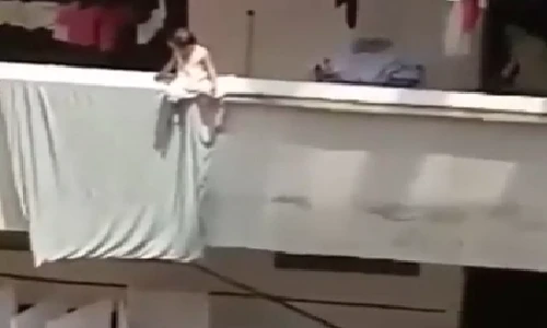 Bé gái ngồi vắt vẻo trên ban công cao ốc... sưởi nắng