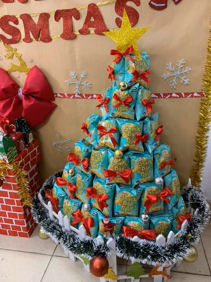 Xếp từ các gói bánh snack, trang trí nơ đỏ và châu nhỏ. Đây là cây thông lý tưởng để trang trí trong các trường học, văn phòng hoặc góc giải trí tại gia, vừa đẹp mắt lại vừa có thể "hóa giải" ngay sau khi mùa lễ kết thúc.