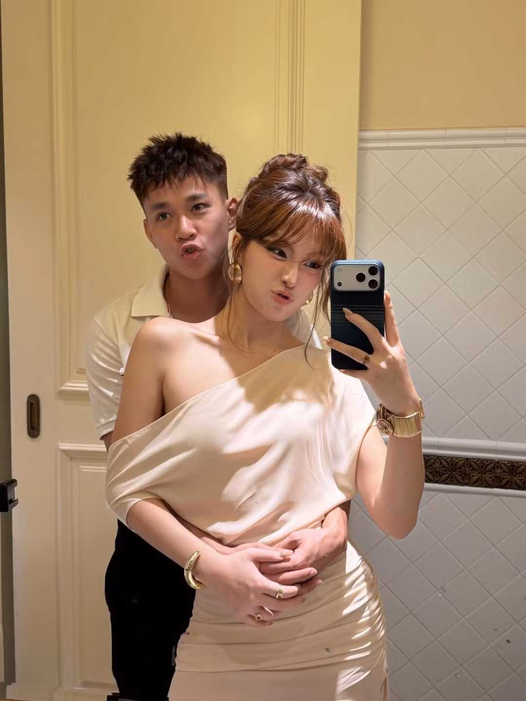 Trong bức ảnh selfie trước gương, Minh Bình xuất hiện với ngoại hình bảnh bao, diện áo polo sáng màu, ôm bạn gái từ phía sau đầy tình cảm. Cả hai cùng làm biểu cảm chu môi đáng yêu, thể hiện sự vui vẻ và thoải mái bên nhau.