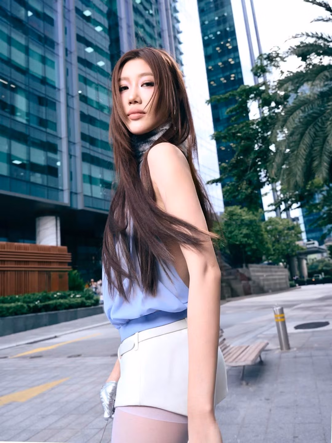 Ở loạt ảnh ngoài phố, sự đối lập giữa bộ đồ thời trang mang chất futuristic với nền tòa nhà kính hiện đại càng làm nổi bật vẻ đẹp thời thượng của cô nàng.