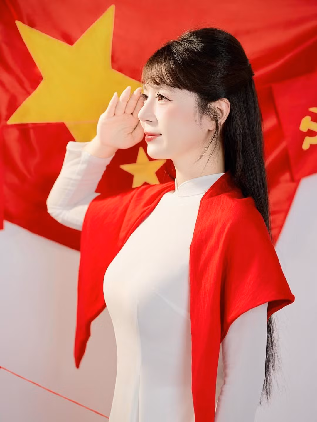 Điểm nhấn là chiếc khăn choàng đỏ rực rỡ và những lá cờ Tổ quốc, cờ Đảng được sử dụng làm phụ kiện, tạo nên một tổng thể hài hòa và tràn đầy cảm xúc. (Ảnh: IGNV)