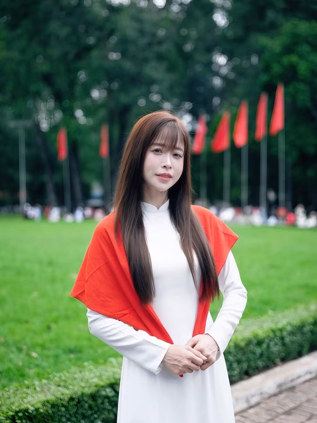 Cô khoác lên mình bộ áo dài trắng thướt tha, kết hợp với chiếc khăn choàng đỏ in sao vàng nổi bật. (Ảnh: FBNV)