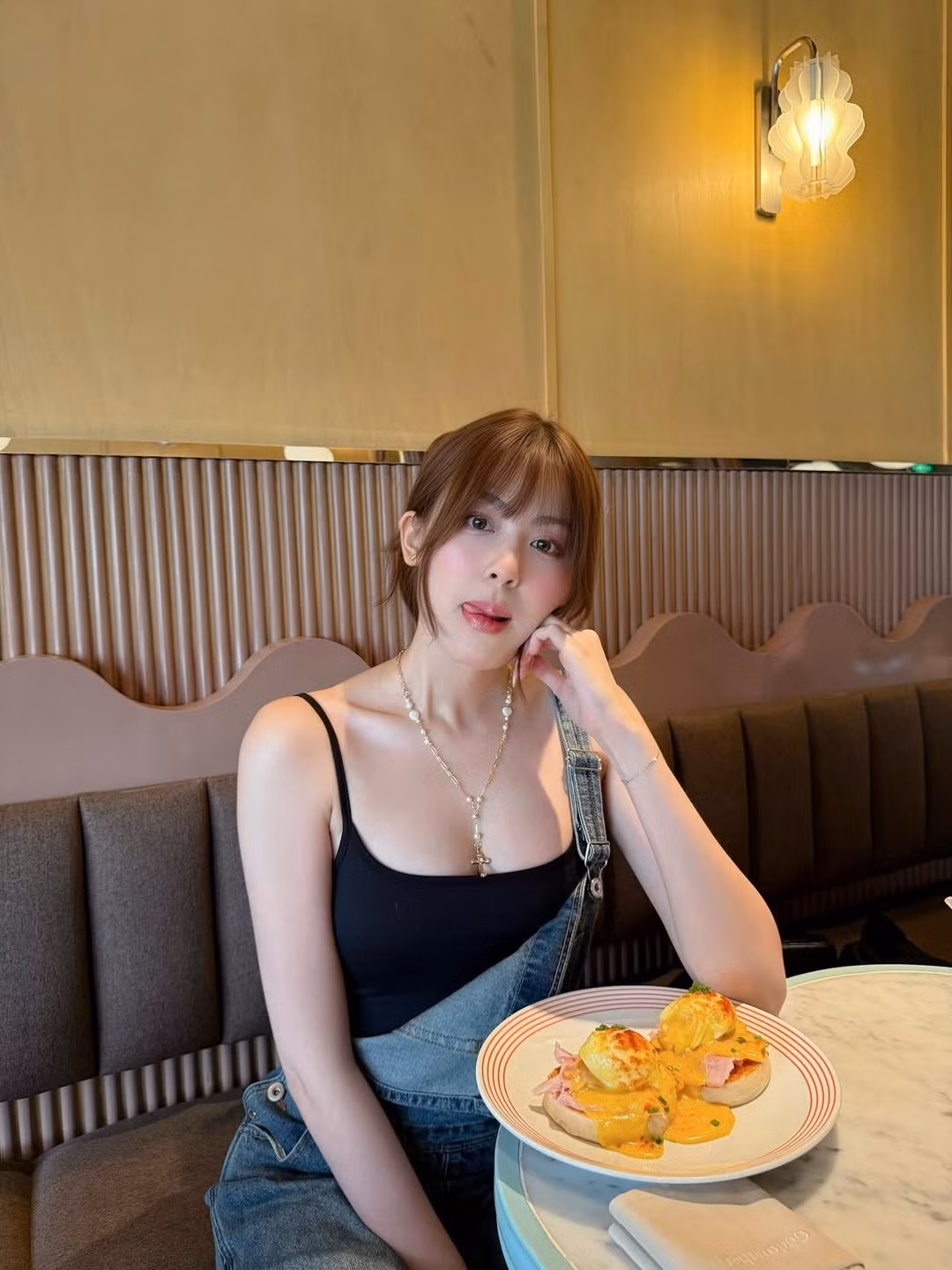 Cô nàng diện quần yếm denim ống rộng, kết hợp bên trong là áo tank top đen đơn giản. (Ảnh: FBNV)