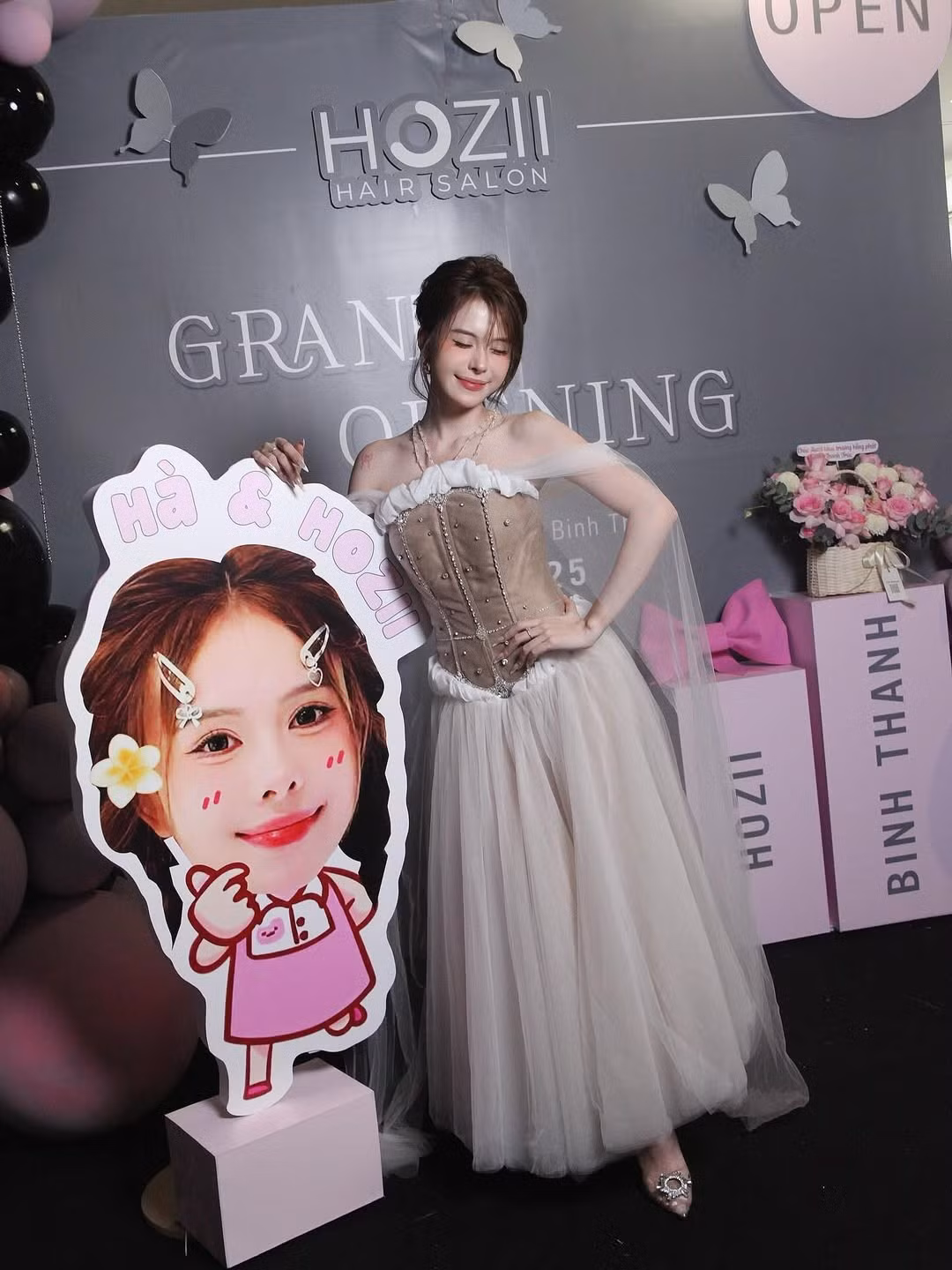 Cô cũng không quên tạo dáng nhí nhảnh bên mô hình chibi dễ thương của chính mình, thể hiện sự vui tươi và gần gũi.