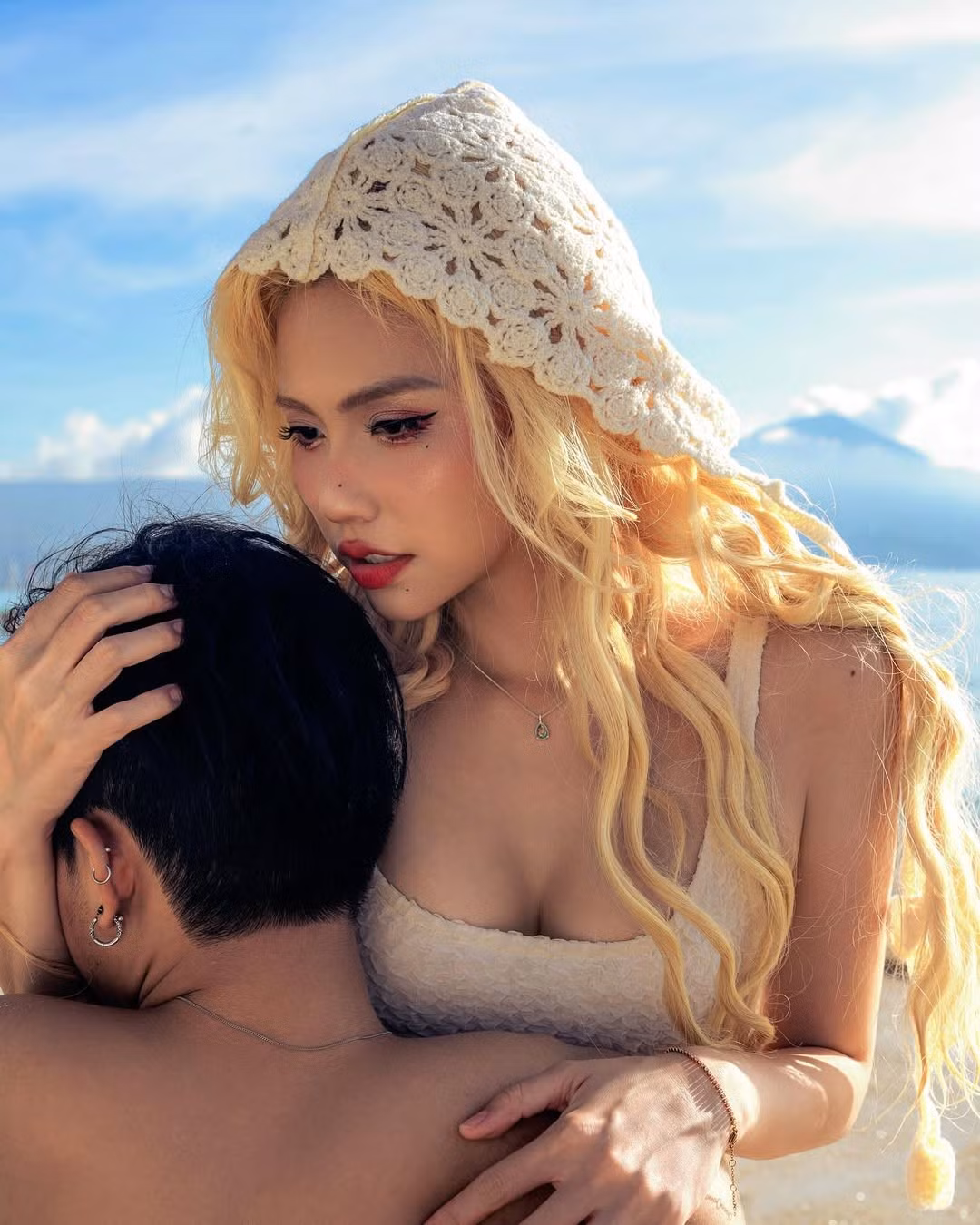 Điểm nhấn nổi bật nhất chính là mái tóc dài bồng bềnh được nhuộm màu vàng bạch kim đầy cá tính, kết hợp cùng chiếc mũ hoặc khăn trùm đầu được làm từ chất liệu len móc màu kem. Kiểu dáng độc đáo của chiếc mũ không chỉ tôn lên vẻ đẹp khác lạ của Châm Sứa mà còn tạo cảm giác huyền bí, pha chút cổ tích.