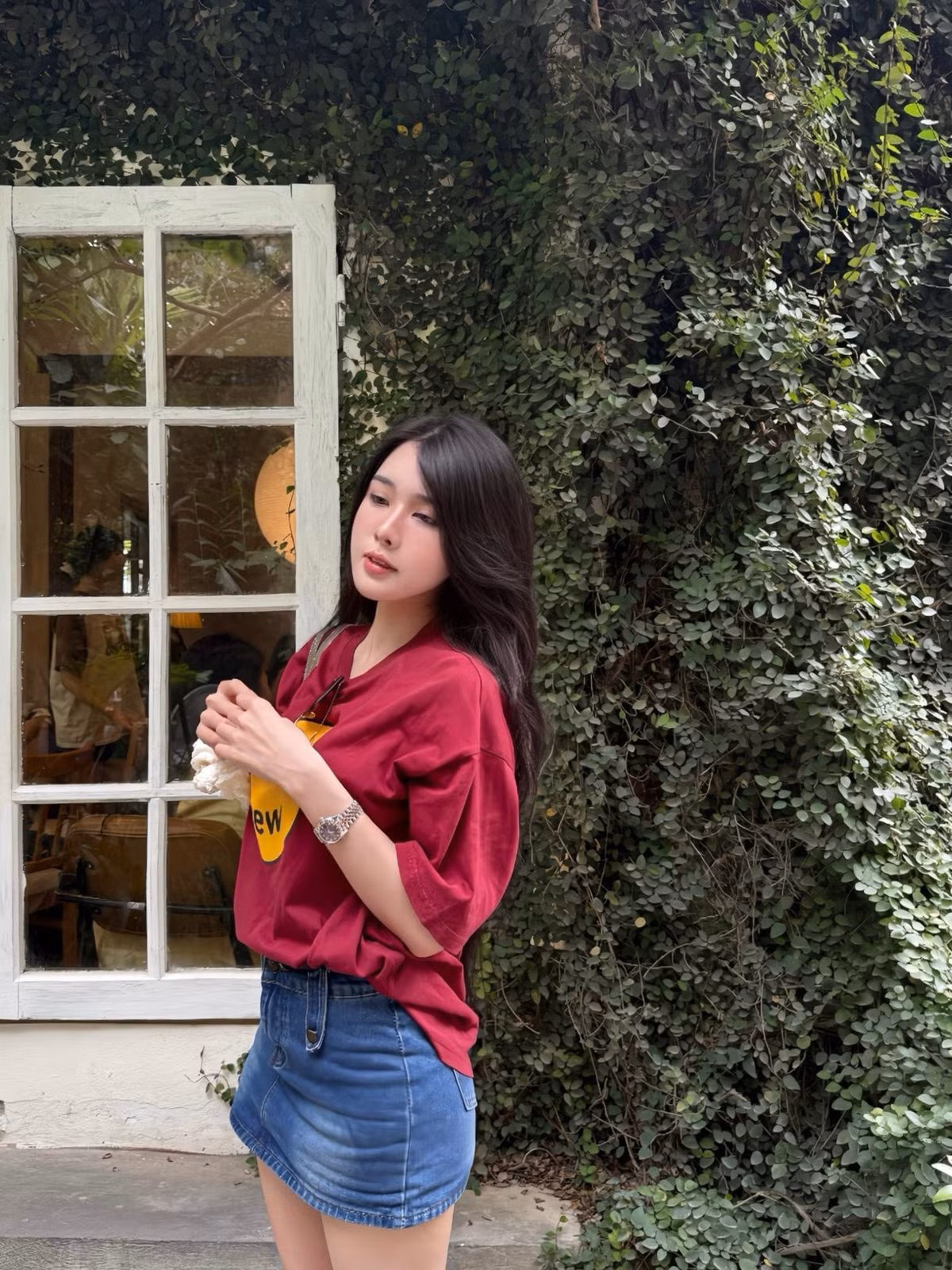 Trong những bức ảnh được chia sẻ, Bích Hạnh chọn cho mình một phong cách đơn giản nhưng cực kỳ "hack dáng" và trendy. Cô nàng diện áo phông oversized màu đỏ đô nổi bật với hình in thương hiệu nổi tiếng, kết hợp cùng chân váy denim chữ A trẻ trung.
