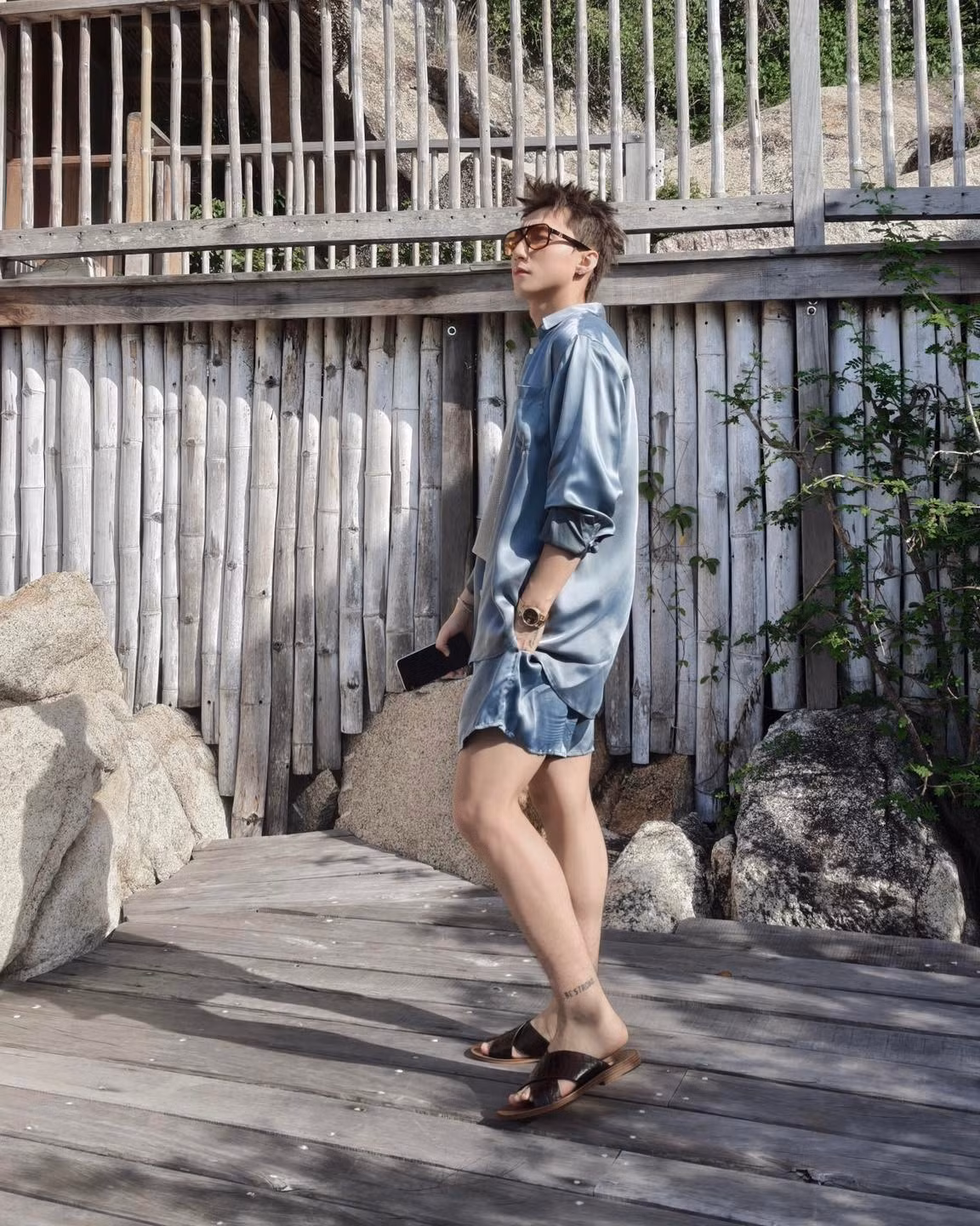 Ở một khoảnh khắc, Sơn Tùng ngồi trên bậc thang gỗ, ánh mắt nhìn xa xăm đầy suy tư dưới chiếc kính râm sành điệu, đôi chân bắt chéo cho thấy sự thư thái tuyệt đối. Ở bức ảnh khác, anh bước đi tự nhiên, ánh mắt vẫn giữ vẻ lãng đãng, đầy thần thái.
