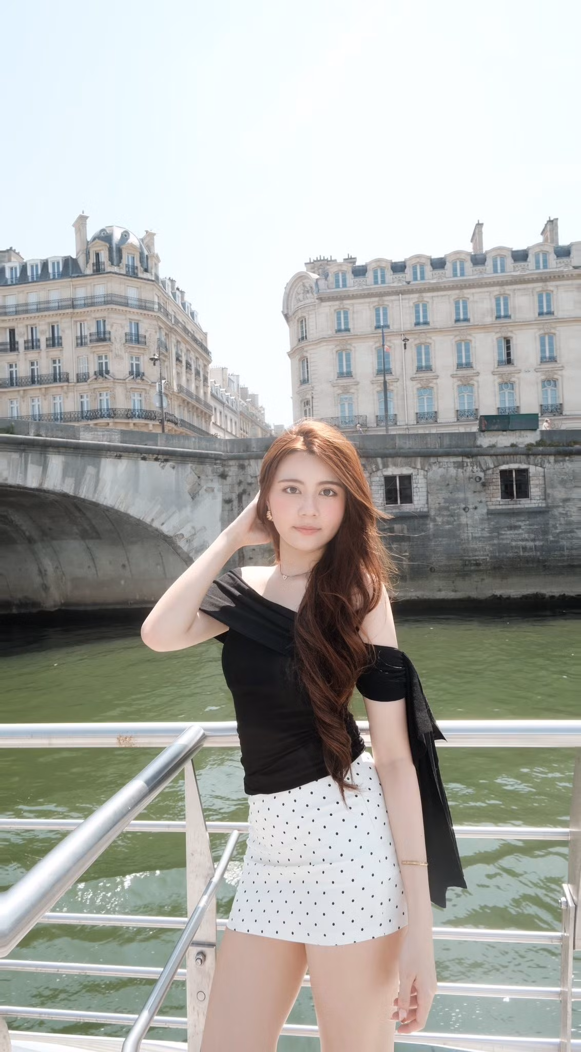 Hạt Dẻ tự tin tạo dáng trên một con thuyền dọc sông Seine, với biểu tượng tháp Eiffel sừng sững phía xa.