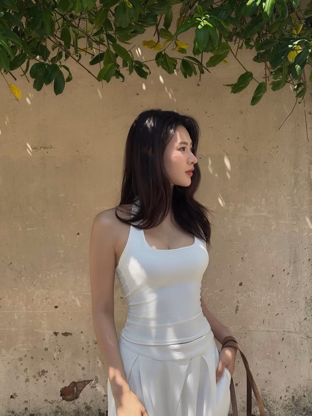 Trong loạt ảnh được đăng tải, Minh Trang diện trang phục toàn bộ màu trắng, bao gồm một chiếc áo hai dây tôn lên bờ vai thon thả và chiếc quần ống rộng với phần cạp được xếp ly điệu đà tôn dáng. (Ảnh: IGNV)