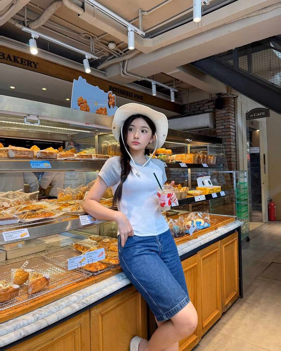 Quỳnh Trương diện áo thun ôm body tay raglan phối xám, quần jean lửng và một chiếc nón rộng vành – outfit “bình thường” đến mức không ai nghĩ nó sẽ viral. Thế nhưng, chính vẻ tự nhiên, năng động, pha chút e ấp trong ánh mắt và nụ cười lại khiến người xem như bị “dính bùa”.