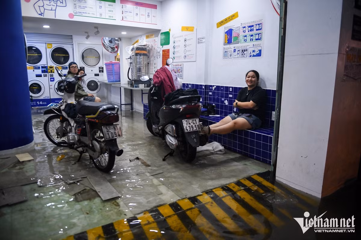 Không chỉ người đi đường, nhà các hộ dân và cửa hàng ven đường cũng bị nước tràn vào. Nước ngập lâu khiến nền sàn một tiệm giặt sấy trên đường Nguyễn Văn Thương bị bong tróc.