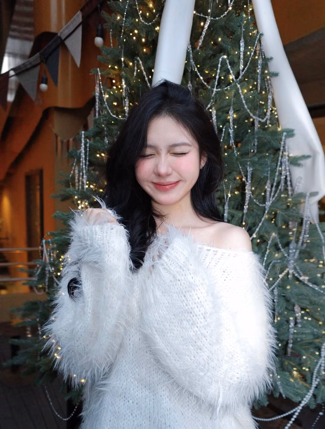 Không chọn những tông màu đỏ rực rỡ truyền thống, cô nàng xuất hiện trong chiếc áo len trễ vai màu trắng tinh khôi với chất liệu lông xù mềm mại. Thiết kế này khéo léo khoe trọn bờ vai trần thon thả và xương quai xanh quyến rũ nhưng vẫn giữ được nét kín đáo, thanh lịch. (Ảnh: IGNV)