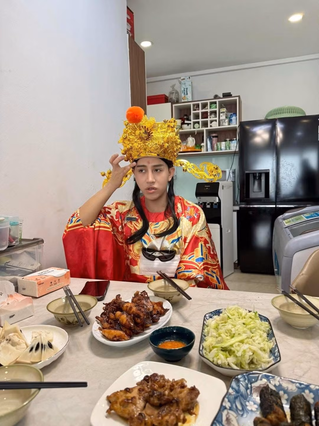 Bức ảnh anh chàng ngồi bên mâm cơm với gương mặt thất thần, tay giữ chiếc mũ "vương giả" đã nhanh chóng trở thành meme mới của cư dân mạng. (Ảnh: Trung Jin)