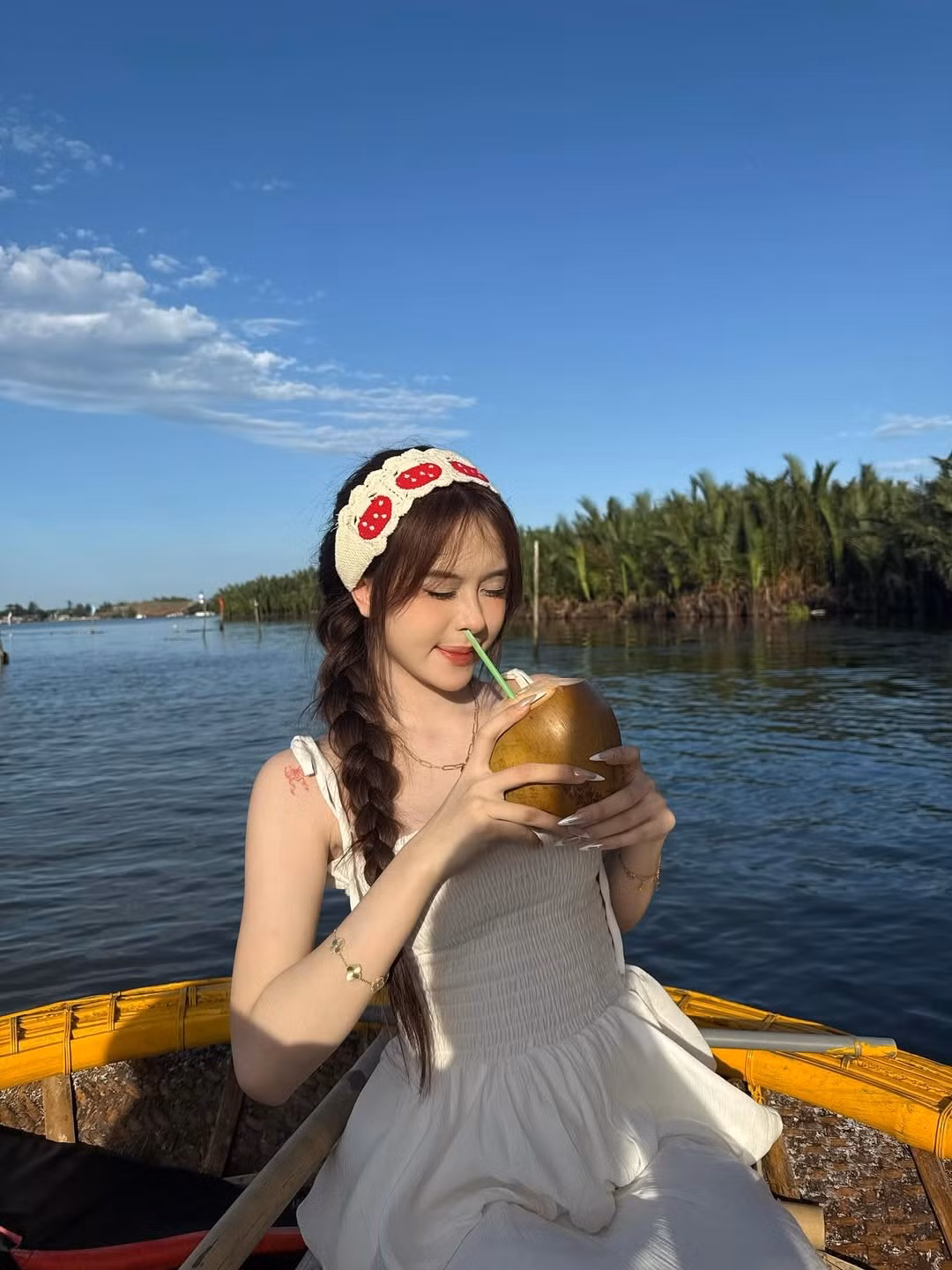 Điểm nhấn là chiếc băng đô cài tóc với họa tiết quả dâu tây dễ thương, cùng mái tóc tết lệch một bên, tạo nên một tổng thể vừa dịu dàng, vừa cá tính.