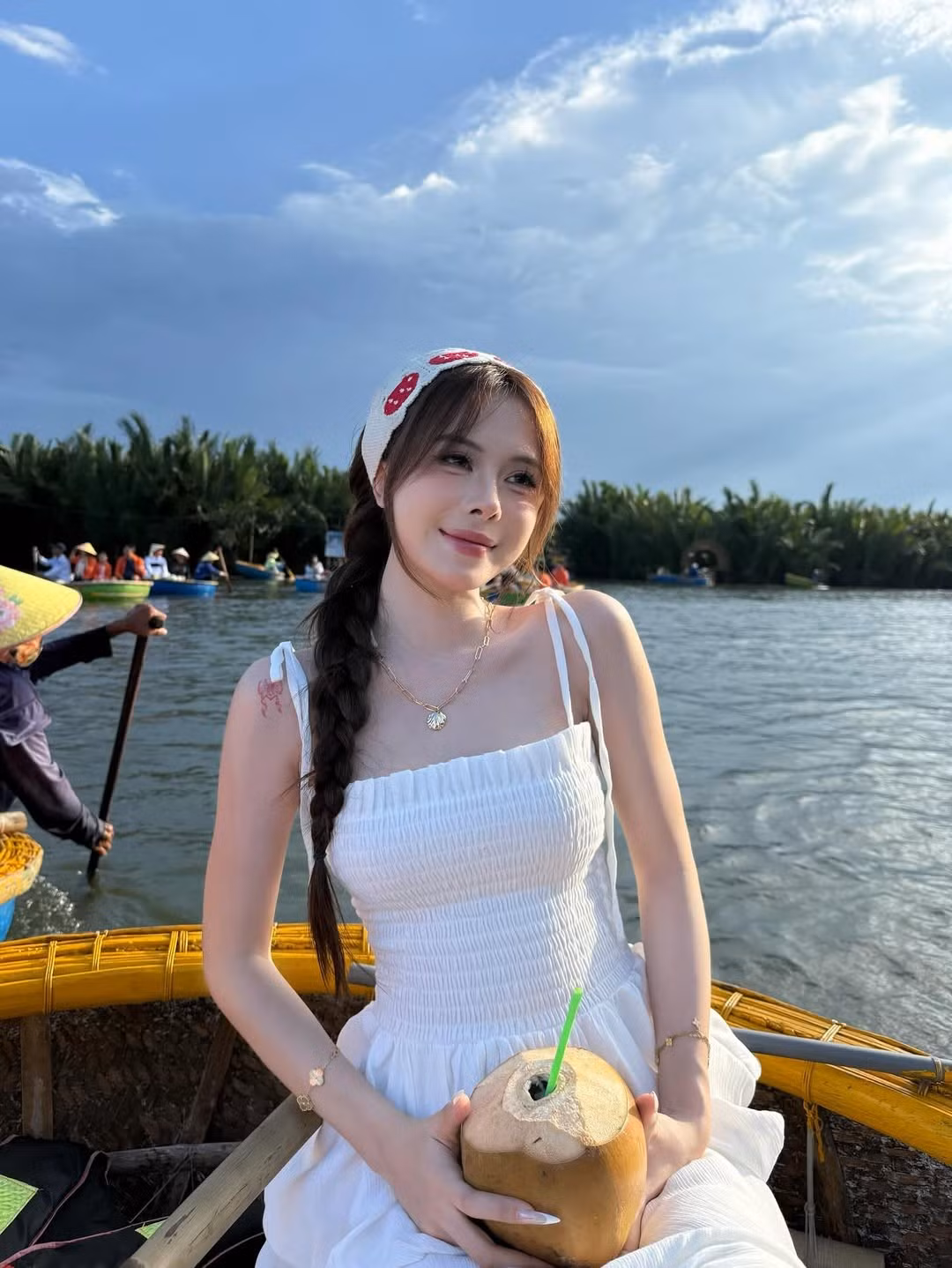 Ngân Hà ngồi trên chiếc thuyền thúng truyền thống, với khung cảnh sông nước hữu tình và hàng dừa xanh ngát phía sau, mang đến cảm giác gần gũi, hòa mình vào thiên nhiên.