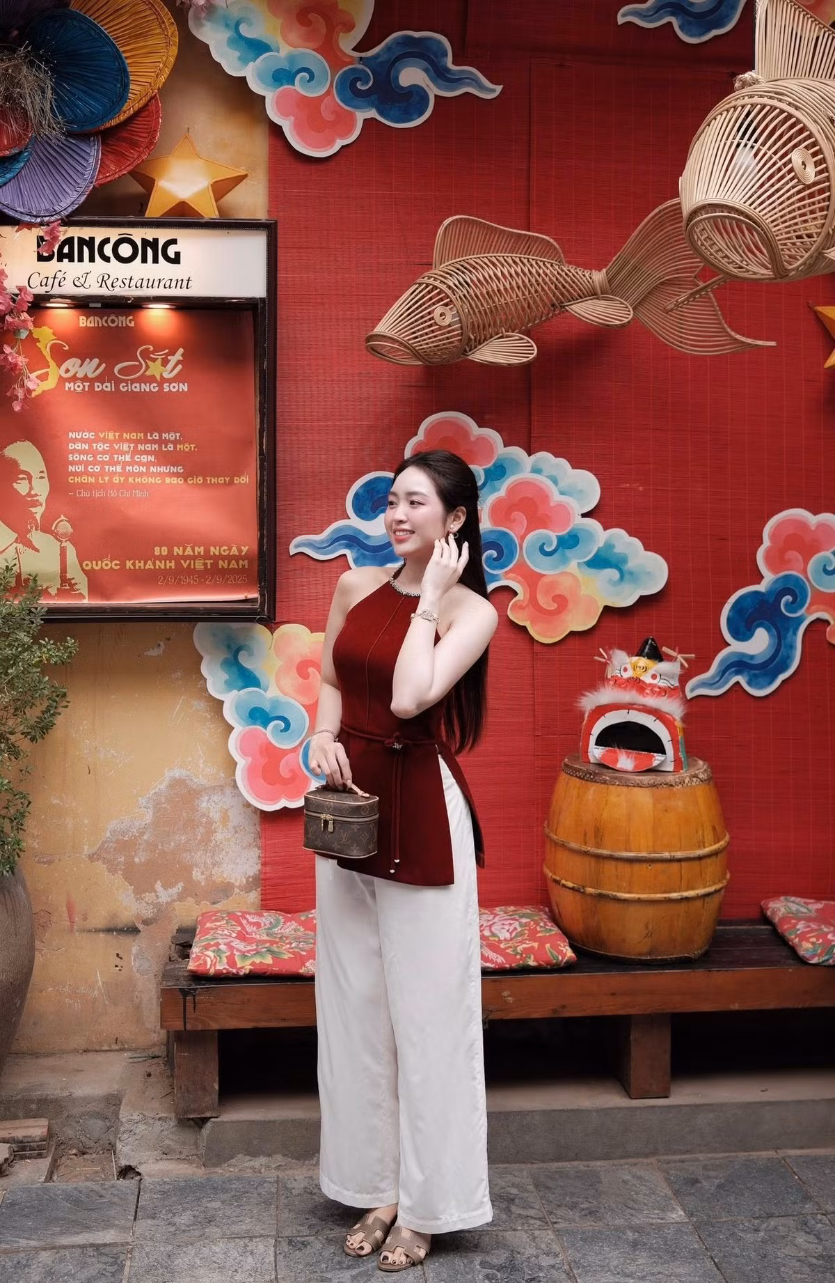 Điều khiến bộ ảnh của Lê Phương Anh trở nên khác biệt chính là bối cảnh chụp ảnh được đầu tư công phu, tái hiện một không gian Trung thu đầy hoài niệm. Các chi tiết trang trí quen thuộc như những con cá chép đan mây treo lơ lửng – biểu tượng của sự thăng tiến, may mắn – và đặc biệt là hình ảnh đầu lân mini đầy màu sắc đặt trên thùng gỗ. (Ảnh: FBNV)
