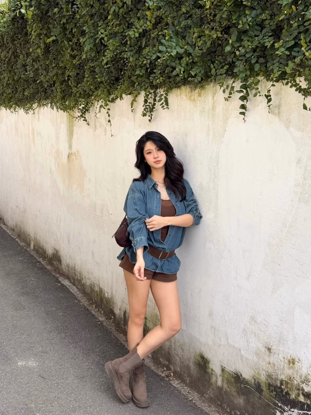 Cô diện bộ trang phục gồm áo màu nâu kết hợp cùng sơ mi denim khoác ngoài, kèm theo quần shorts ngắn đồng màu và boots da lộn cá tính. (Ảnh: IGNV)