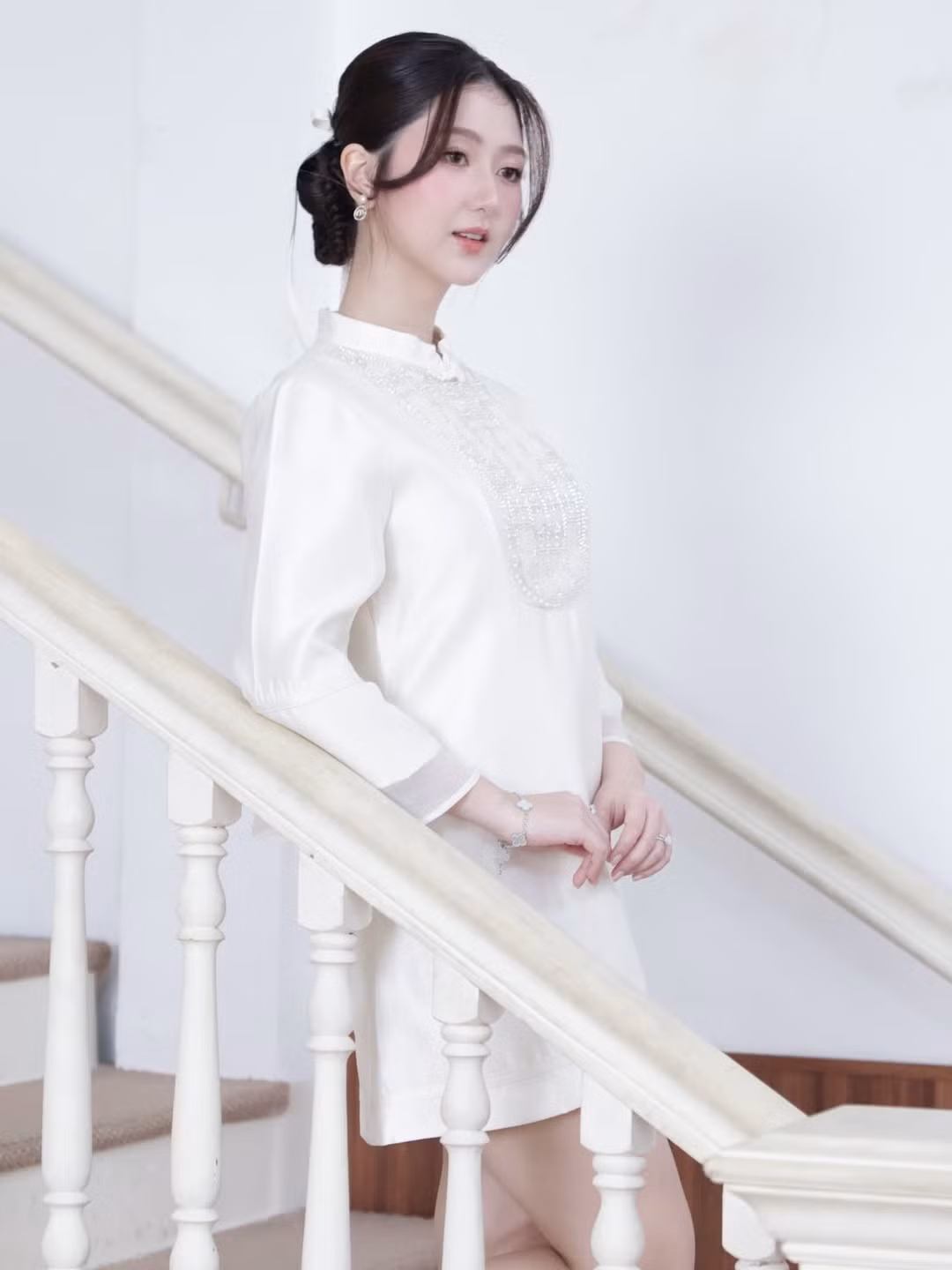 Cô nàng chọn kiểu tóc búi gọn gàng phía sau, điểm xuyết bằng dải ruy băng trắng thắt nơ dài. Kiểu tóc này giúp khoe trọn đường nét gương mặt thanh tú và phần cổ áo thanh lịch. (Ảnh: IGNV)