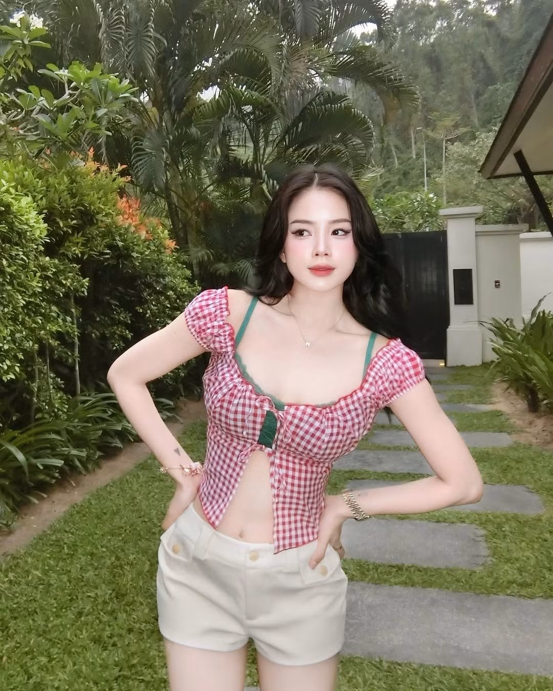 Diện trang phục trẻ trung với áo croptop caro đỏ trắng và quần short kem, cô mang đến hình ảnh vừa năng động, vừa gợi cảm nhưng không kém phần ngọt ngào.