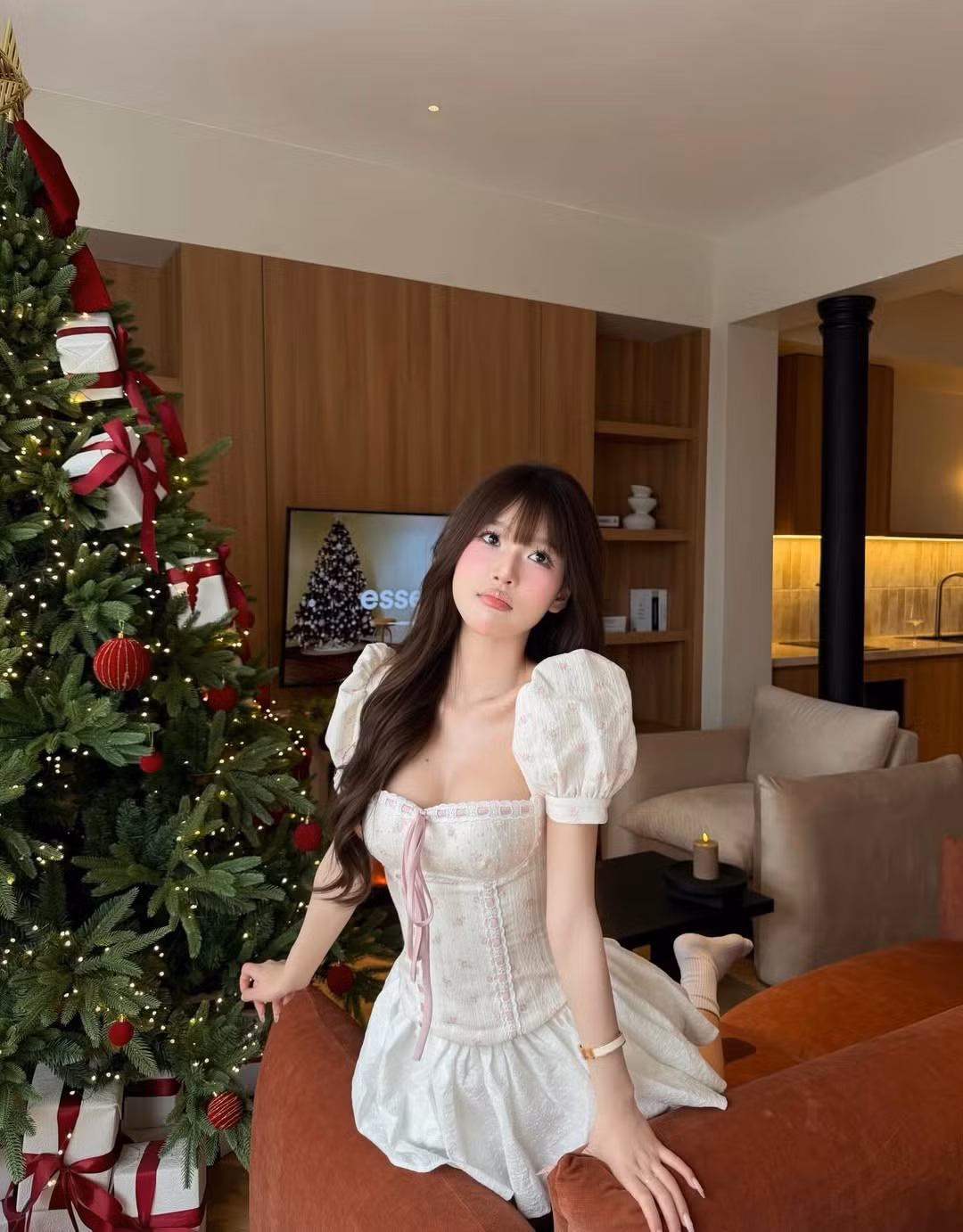 Bộ ảnh được thực hiện trong một không gian cực kỳ sang chảnh nhưng không kém phần ấm cúng. Chiếc cây thông Noel khổng lồ được trang trí tỉ mỉ với những hộp quà thắt nơ đỏ, đèn led vàng dịu nhẹ và bếp lửa hồng rực cháy phía sau tạo nên một bối cảnh hoàn hảo cho những khung hình "triệu tim". (Ảnh: IGNV)