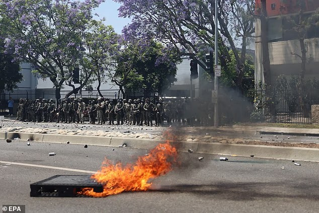 A pallet burns as protesters and security personnel clash near a Home Depot in Paramount. Photo: EPA. bieu2.png