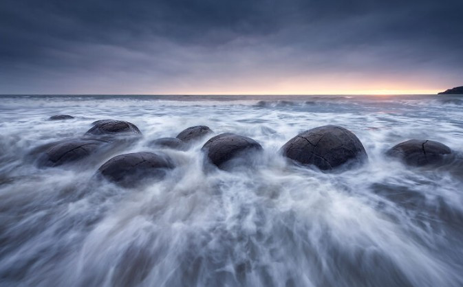 Batu Moeraki yang terkenal saat matahari terbit. Bola-bola raksasa ini, yang terbentuk dari batuan sedimen purba puluhan juta tahun lalu, terletak di Pantai Koekohe di pesisir Otago. new2.png