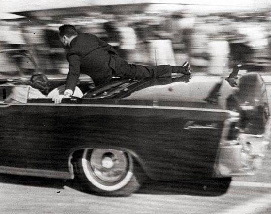 Nhân viên mật vụ Clint Hill nhảy lên chiếc limousine để làm lá chắn bảo vệ Tổng thống Kennedy và Đệ nhất phu nhân ngay sau khi tiếng súng nổ vang lên. sat2.png
