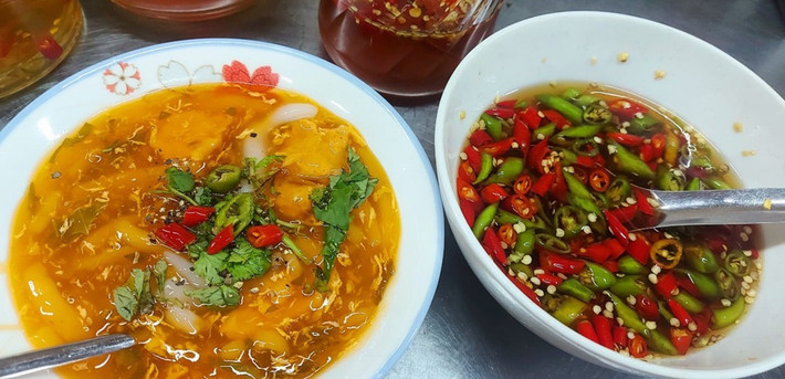Cạnh đó, bánh canh Nam Phổ bà Vinh cũng là món không nên bỏ lỡ. Tô bánh canh có sắc đỏ cam đặc trưng từ gạch cua, nước dùng sánh đậm, sợi bánh mềm dai, điểm xuyết thêm chả và hành lá. Hương vị ngọt thanh, cay nhẹ đúng chuẩn ẩm thực xứ Huế nhưng đã được biến tấu hợp khẩu vị Đà thành. Ảnh Internet