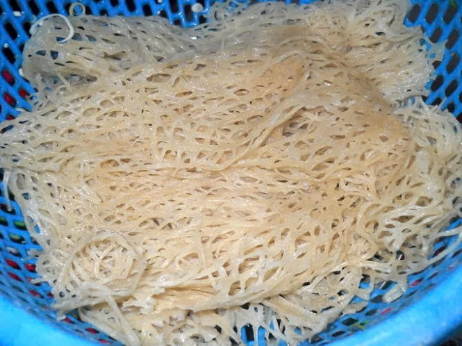 Quy trình làm phở sắn tuy đơn giản về nguyên liệu nhưng đòi hỏi sự tỉ mỉ và kinh nghiệm. Củ sắn sau khi lột vỏ, ngâm khử nhựa sẽ được xay nhuyễn, lọc bột rồi đem phơi cho ráo. Phần tinh bột thu được hòa nước, nấu chín một phần để tạo độ kết dính, sau đó nhào thành khối dẻo và cho vào khuôn đan hoặc vỉ mắt lưới. Lúc này, người làm khéo léo dàn đều bột lên mặt vỉ để tạo thành tấm phở với những sợi tròn li ti liên kết như chài cá. Ảnh