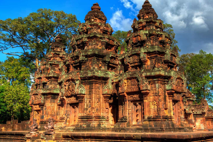 Nếu yêu thích nghệ thuật, Banteay Srei – còn gọi là “viên ngọc hồng” của Campuchia – sẽ khiến du khách ngỡ ngàng. Ngôi đền nhỏ được xây bằng đá sa thạch đỏ, nổi bật với những đường chạm khắc tinh vi đến mức nhiều nhà nghiên cứu gọi đây là “bản giao hưởng hoàn hảo của đá và ánh sáng”. Ảnh iVIVU