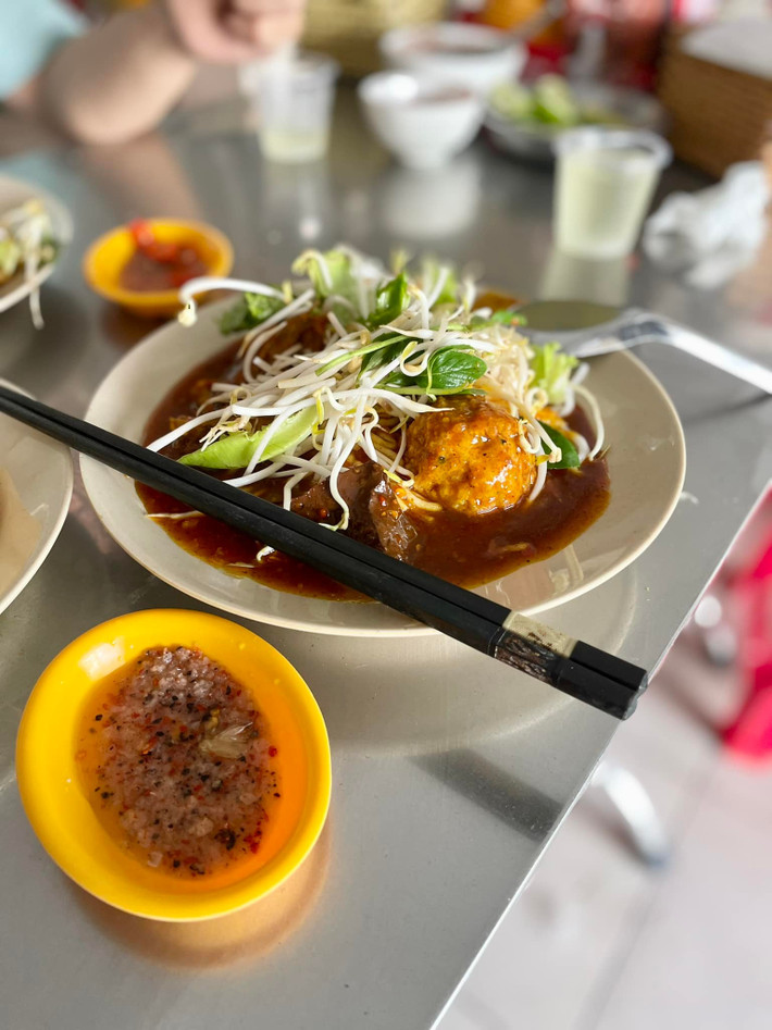 Điểm nhấn tiếp theo là phần nước sốt cà ri – “linh hồn” của món bánh. Nước sốt được nấu từ các loại gia vị như đinh hương, đại hồi, bột nghệ, quế chi, hạt mùi, ớt khô... tạo nên màu sắc đỏ au bắt mắt cùng hương thơm quyến rũ. Nồi cà ri đặt ngay trước cửa quán luôn nghi ngút khói, thơm nức, khiến thực khách khó lòng đi ngang mà không dừng bước. Ảnh Bánh tằm cay chú Đạo