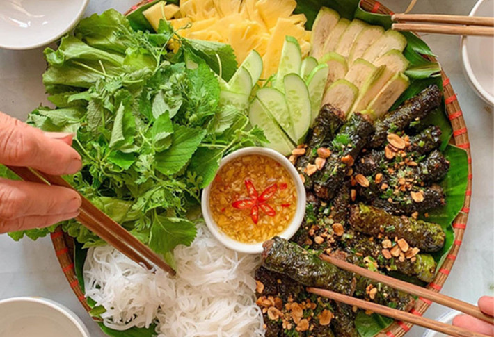 Khi phố vừa lên đèn, mùi thơm của bò cuốn lá lốt nướng trên than hồng lan tỏa khắp các con hẻm. Những cuốn bò nhỏ nhắn, được nướng chín tới, chấm cùng mắm nêm, ăn kèm bún tươi và rau sống là lựa chọn lý tưởng cho bữa xế hoặc tối nhẹ nhàng. Phố Phan Bội Châu và quanh chợ Xóm Mới là điểm đến quen thuộc của dân sành ăn. Ảnh MIA