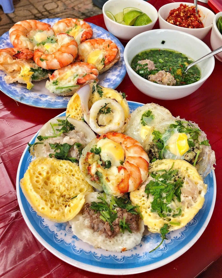 Bánh căn Nha Trang được đúc trong khuôn đất, nhân tôm, mực, trứng cút hoặc thịt băm. Khi bánh chín, người bán nhanh tay gắp ra đĩa, ăn kèm mỡ hành, xoài xanh bào sợi và chén nước chấm pha từ mắm nêm, nước cá hoặc nước mắm tỏi ớt. Quán bánh căn Tháp Bà, hẻm Nguyễn Trãi hay đường Tô Hiến Thành đều rất nổi tiếng, giá chỉ từ 20.000 – 30.000 đồng/phần. Ảnh MIA
