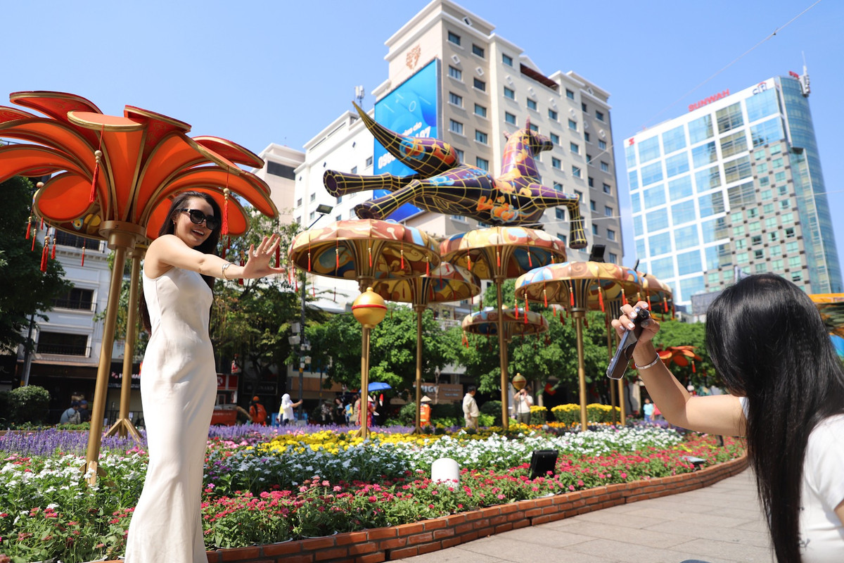 Thời tiết TP HCM giữa trưa đến cuối chiều vẫn oi bức, nắng nóng nhưng nhiều người vẫn tranh thủ "check in" đường hoa Nguyễn Huệ trong ngày cuối của kỳ nghỉ Tết.