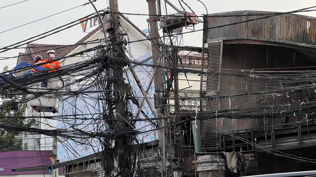Hệ thống dây cáp trước cửa hàng bị cháy, hư hỏng sau vụ cháy. Nhân viên điện lực, viễn thông... nỗ lực khắc phục.