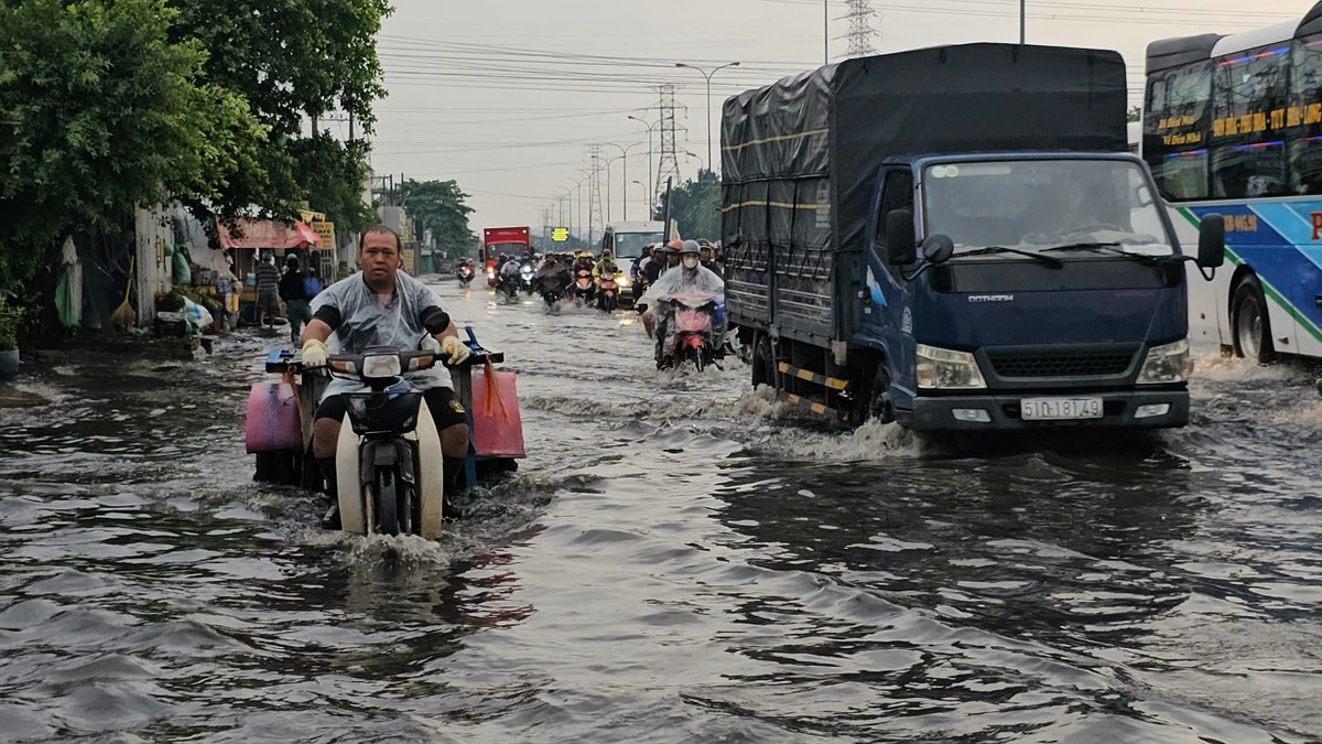Người dân bì bõm di chuyển trong dòng nước đen ngòm trên đường sau mưa.