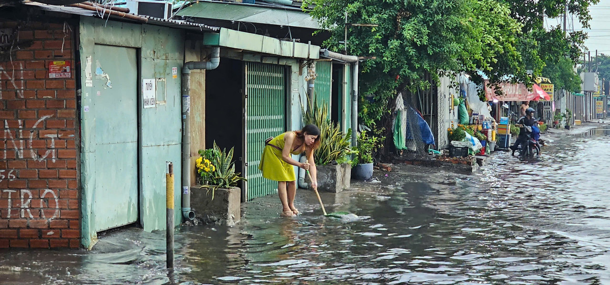 Người dân khơi thông miệng cống để nước ngập nhanh thoát trên đường Lê Đức Anh.